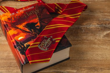 25.03.25 Lviv Ukrayna. Harry Potter kitaplarından oluşan bir koleksiyon, büyüleyici atmosferi geliştirmek için Hogwarts kravatıyla eşleştirilmiş Fransızca ve Bulgarca farklı kapaklar sergiliyor..
