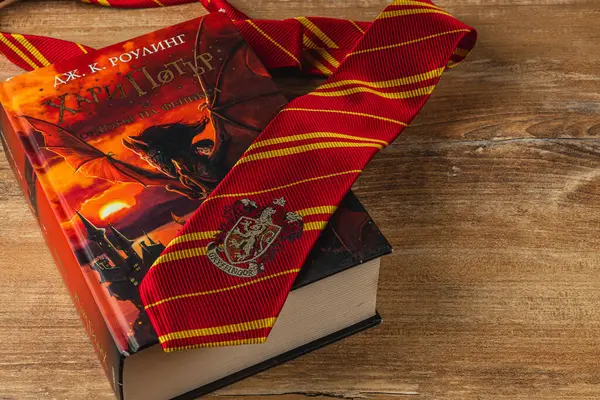 25.03.25 Lviv Ukrayna. Harry Potter kitaplarından oluşan bir koleksiyon, büyüleyici atmosferi geliştirmek için Hogwarts kravatıyla eşleştirilmiş Fransızca ve Bulgarca farklı kapaklar sergiliyor..