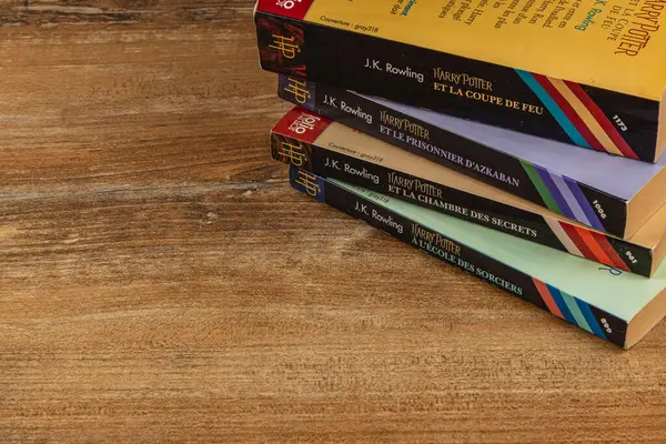 25.03.25 Lviv Ukrayna. Bir Hogwarts mektubu ve temalı aksesuarların yanı sıra rustik ahşap bir yüzey üzerinde başlıkları bulunan Fransızca ve Bulgarca Harry Potter kitaplarından oluşan bir koleksiyon..