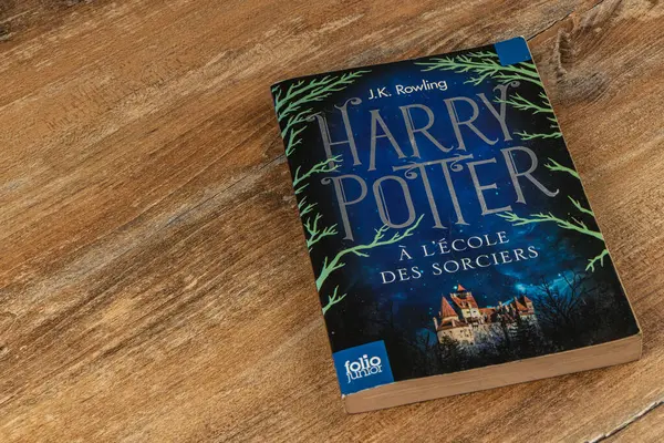 25.03.25 Lviv Ukrayna. Bir dizi Harry Potter kitabı ahşap bir masada yatıyor. Bir kitabın kapağında, ikonik Hogwarts imgeleri ve sihirli elementler içeren Fransızca bir başlık yer alıyor..