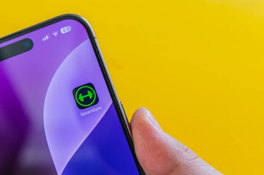 03.26.25 Lviv Ukrayna Bir kişi, parlak sarı bir arkaplan karşısında bir fitness uygulaması simgesi içeren bir akıllı telefon tutuyor,.