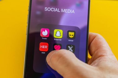 03.26.25 Lviv Ukrayna A, çeşitli sosyal medya simgelerini gösteren bir akıllı telefon ekranı ile etkileşim halindedir. Parlak renkler ve canlı bir arkaplan kullanımda olan uygulamaları vurgula.