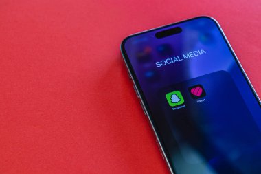 03.26.25 Lviv Ukrayna Akıllı telefon ekranında canlı kırmızı bir arkaplan karşısında sosyal medya uygulamaları, modern iletişimin dijital bağlantısını vurguluyor.