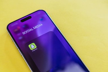 03.26.25 Lviv Ukrayna. Akıllı telefon ekranında canlı sarı bir arka plan üzerinde sosyal medya uygulaması var. Günlük hayattaki modern dijital iletişim manzarasını vurguluyor..