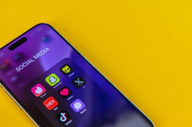 03.26.25 Lviv Ukrayna, parlak sarı arka planda çeşitli sosyal medya uygulamalarını gösteren bir akıllı telefon ekranının yakın görüntüsü. Ekran canlı ve görsel olarak çarpıcı..