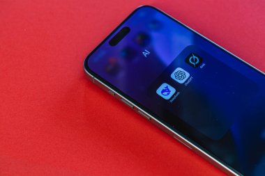 03.26.25 Lviv Ukrayna. Bir akıllı telefon, yapay zeka uygulamalarının simgelerinin yer aldığı canlı kırmızı bir yüzeye yerleştirilir. Ekran, gündüz vakti parlak ve modern bir tasarımı yansıtıyor..
