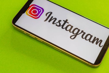 03.26.25 Lviv Ukrayna akıllı telefon Instagram uygulamasını gösteren canlı yeşil bir yüzeye dayanır. Parlak renkler, dijital etkileşimi vurgulayan canlı bir atmosfer yaratıyor..