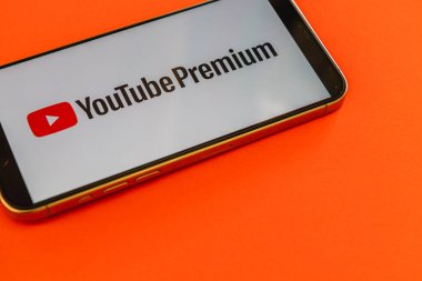 03.26.25 Lviv Ukrayna Akıllı bir telefon YouTube Premium logosunu canlı turuncu bir arkaplan üzerinde barındırıyor, platformun içerik sunumlarını ve abonelik seçeneklerini vurguluyor.