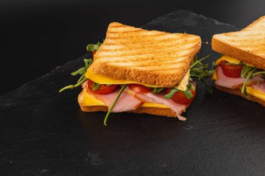 Lezzetli ızgara peynirli sandviç. İçinde jambon, ıspanak, roka ve taze domates ve mükemmel kızarmış ekmek var. Öğle yemeği, kahvaltı veya doyurucu bir atıştırmalık için ideal..