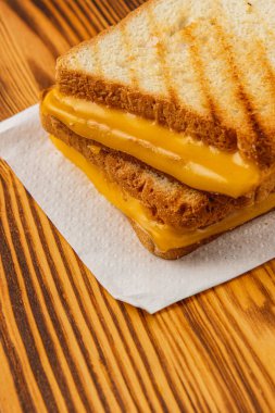 Lezzetli bir ızgara peynirli sandviç beyaz bir peçeteye güzelce yerleştirilir, mükemmel bir şekilde erimiş peyniri altın, kızarmış ekmek dilimlerinin arasına yerleştirilir. Kahvaltı, brunch ya da atıştırmalık için ideal..