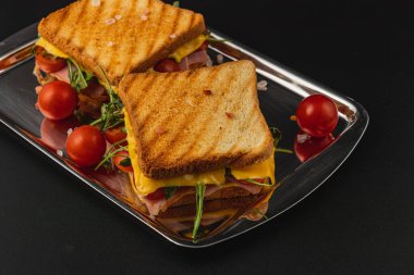 Bu ızgara sandviç, kıtır ekmek üzerinde servis edilen jambon, erimiş peynir, taze ıspanak ve domates katmanlarını içerir. Öğle yemeği için mükemmel ya da doyurucu bir atıştırmalık olarak..