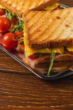 Jambon, taze ıspanak, roka ve olgun domateslerle kaplı lezzetli ızgara peynirli sandviç, kızarmış ekmeğin üzerinde servis edilir. Öğle yemeği, brunch ya da lezzetli bir atıştırmalık için mükemmel..