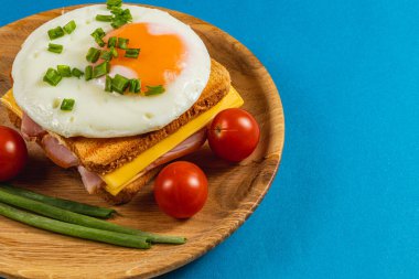 Sağlıklı bir kahvaltı sandviçi peynir, jambon ve kıyılmış yeşil soğanla süslenmiş ve olgun domateslerle servis edilen güneşte pişmiş yumurta katmanlı ekmek içerir..