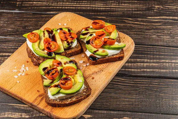 Taze hazırlanmış açık yüzlü sandviçler üzerinde salatalık dilimleri, kiraz domatesleri ve balzamik jöleli siyah ekmek içeriyor. Hafif bir yemek veya atıştırmalık için mükemmel..