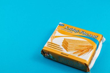 Lviv Ukrayna 04.02.25 Sarı ve beyaz bir paket gevrek buğday çerezi parlak mavi arkaplan karşısında duruyor, çekici tasarım ve dokusunu sergiliyor.