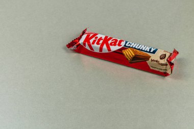 Lviv Ukrayna 04.02.25 Bir KitKat tıknaz çubuğu pürüzsüz bir ışık yüzeyinin üzerinde duruyor, kendine özgü ambalajını ve çikolata katmanlarını gözler önüne seriyor, çerez aşıklarını baştan çıkarıyor..