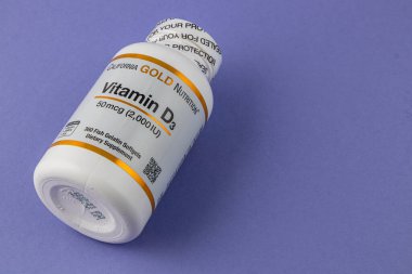 24.03.25 Lviv Ukrayna Bir şişe D3 vitamin takviyesi mor bir yüzeye yerleştirilir. Etiket, D3 vitamininin sağlık için dozajını ve faydalarını vurgular.