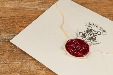 25.03.25 Lviv Ukrayna. Hogwarts 'ın kırmızı balmumuyla mühürlenmiş kabul mektubu ahşap bir masada duruyor, temalı aksesuarlarla çevrili, büyüleyici sihir dünyasını çağrıştırıyor..