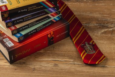 25.03.25 Lviv Ukrayna. Harry Potter kitaplarından oluşan bir kolleksiyon, Hogwarts kravatının yanında ahşap bir yüzeye dizildi. Büyücü dünyasının renkli kapaklarıyla cazibesini sergiliyor..