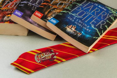 25.03.25 Lviv Ukrayna. Fransızca ve Bulgarca Harry Potter kitaplarından oluşan bir koleksiyonun yanında klasik kırmızı ve altın bir Hogwarts kravatı sergilenerek büyülü bir atmosfer yaratıldı..