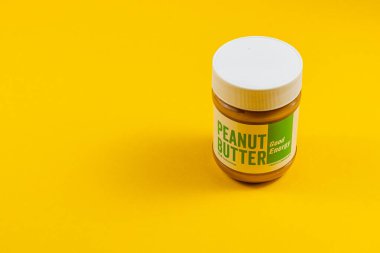 Lviv Ukrayna 04.02.25 parlak sarı bir yüzey üzerine yerleştirilmiş bir kavanoz fıstık ezmesi çekici ambalajını gösteriyor. Kalın etiket ayarların enerjik titreşimini ekler.