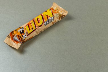 Lviv Ukrayna 04.02.25 Cesur aslan damgalı bir çikolata pürüzsüz gri bir yüzeye dayanır. Ambalaj canlı renkler ve baştan çıkarıcı bir tasarım sergiler.