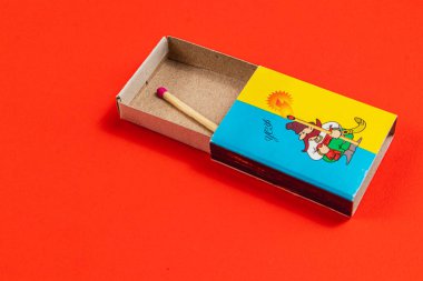Lviv Ukrayna 04.02.25 Çizgi film karakterinin yer aldığı renkli bir kibrit kutusu parlak kırmızı bir arkaplanda oturur ve oyuncu tasarımı vurgular..