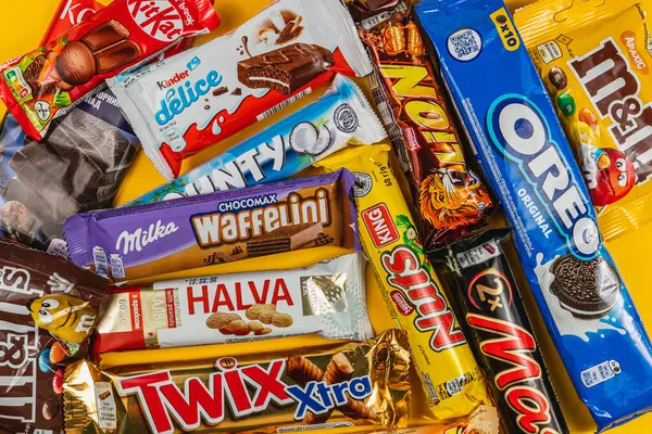 Lviv Ukrayna 04.02.25 bir dizi popüler çikolata ve abur cubur ahşap bir yüzeye yayılarak canlı ambalajlar sergiliyor. Şeker ya da kutlama için mükemmel..