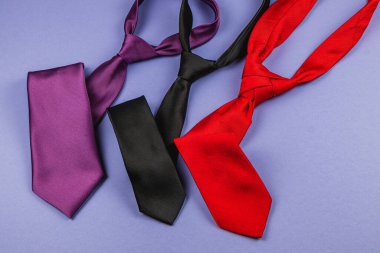 Mor, siyah ve kırmızı renkli canlı bağlardan oluşan bir kolleksiyon mavi arka planda serili. Babalar günü ya da doğum günleri için mükemmel hediyeler, babalar ve erkekler için kutlamayı geliştirmek..
