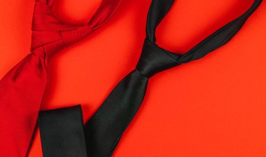 Parlak turuncu bir yüzeye serilmiş kırmızı ve siyah renkli kravatlar Babalar Günü kutlamaları, doğum günleri ve erkekler için özel günler için düşünceli hediyeleri sembolize eder..