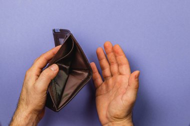 Bir erkek işadamı, ekonomik durgunluk sırasında yaşanan mali sıkıntıları ve tasarruf kayıplarını vurgulayan, endişe ifadesi taşıyan boş bir deri cüzdan taşıyor..