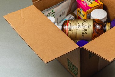 Lviv Ukrayna 10.04.25 Vitamin, mineral ve besin ürünleri de dahil olmak üzere çeşitli sağlık maddeleriyle dolu bir karton kutu düz bir yüzeyde sergilenmektedir..