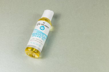 Lviv Ukrayna 10.04.25 Bir şişe Fas argan yağı pürüzsüz gümüş bir yüzeye dayanır. Yağ altın değerindedir ve cilt ve saç için hidrasyon sağlar..