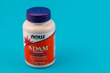 Lviv Ukrayna 10.04.25 Şişede canlı mavi arka plana yerleştirilmiş erkek multivitamin kapsülleri var. Sergide genel sağlık ve sağlığı destekleme amaçlı yararlı malzemeler yer alıyor..