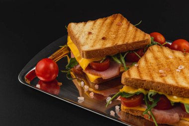 Peynir, jambon, ıspanak ve domates katmanlı ağız sulandırıcı bir sandviç. Brunch, öğle yemeği ya da hızlı bir atıştırma için mükemmel. Taze hazırlanmış ve kızarmış ekmeğin üzerinde servis edilmiş..