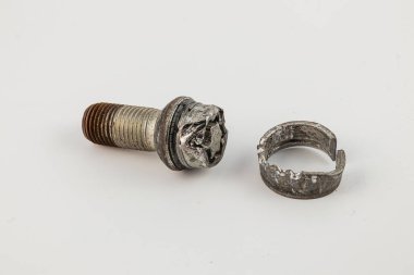 Kırık bir cıvata ve tekerlek bileşeni tarafsız bir yüzeyde duruyor. Bu da bir araç ya da ekipman parçasının mekanik arızası ya da parçalanması anlamına geliyor..