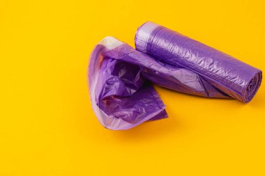 Canlı bir ekran, dokularını ve renklerini vurgulayan çarpıcı sarı bir arkaplana karşı katlanmış bir bölümün yanında mor bir plastik rulo içerir..