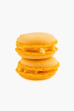 Kremalı bir dolguyla dolu iki canlı sarı badem kurabiyesi basit bir arkaplana karşı üst üste istiflenerek hassas dokularını ve renklerini sergiliyorlar..