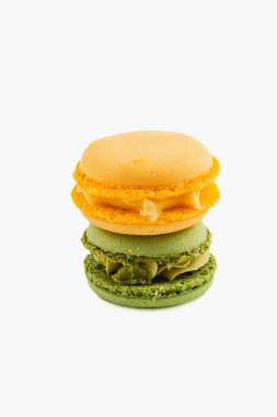 Canlı renklerde üç badem kurabiyesi bir yığın halinde dizilir. Üstteki makaron sarı, ortası turuncu, alttaki yeşil, enfes dokular sergiliyor..