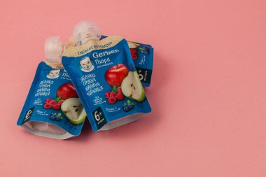 Lviv Ukrayna 05.06.25 Renkli meyve püresi kesesi canlı pembe bir arka plana karşı düzenlenmiştir, bebekler ve yeni yürümeye başlayanlar için uygun lezzetler sergilenmektedir..