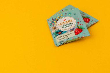 Lviv Ukrayna 05.06.25 siyah ve yeşil çay karışımı için renkli ambalajlar canlı sarı bir yüzeye oturmuş çilek ve çiçek desenleri dikkat çekiyor..