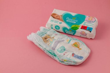 Lviv Ukrayna 05.06.25 Renkli tasarımları olan bir bebek bezi yumuşak pembe bir arka planda paketlenerek işlevselliğini ve ebeveynler için cazibesini gösteriyor..