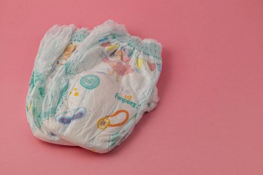 Lviv Ukrayna 05.06.25 Üç bebek bezi yumuşak pembe bir arka plana yerleştirilir ve oyuncu tasarımları sergilenir. Bebeklerinin ihtiyaçları ve rahatlığı için ebeveynler için ideal..