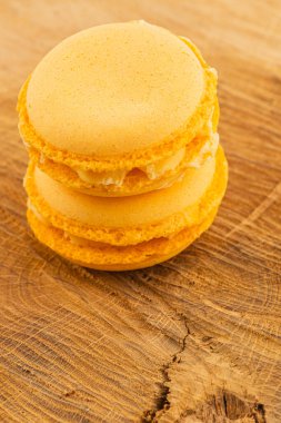 İki canlı turuncu badem kurabiyesi kırsal bir ahşap masaya güzelce istiflenir. Pürüzsüz yüzeyleri ışıldıyor ve hoş dokularına daha yakından bakmalarını sağlıyor..