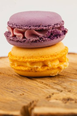 Canlı mor ve sarı renkte ince işçilikli badem kurabiyeleri kırsal ahşap bir yüzey üzerinde oturur ve her tatlı aşığı için güzel bir ziyafet sunar..