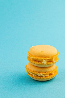 Sarı badem kurabiyeleri pürüzsüz mavi bir yüzeye düzgünce istiflenir. Zarif dokularını ve kremlerini göz alıcı bir düzende sergilerler..