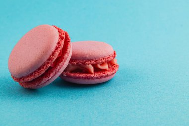 İki yumuşak pembe makarna canlı turkuaz bir arka planda yan yana yerleştiriliyor. Yumuşak dokularını ve merkezlerini sergiliyorlar. Tatlıları sevenler için mükemmel..