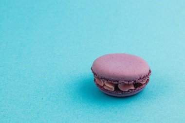 Tek bir mor badem kurabiyesi canlı, mavi bir yüzeyde oturur ve narin dokusunu ve dokusunu ön plana çıkarır. Tatlıdan ve tatlıdan hoşlanan herkes için mükemmel..