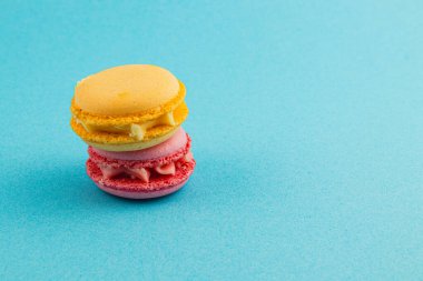 İki canlı badem kurabiyesi, biri sarı ve biri pembe, hoş dokularını ve renklerini sergiliyorlar..