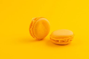 İki canlı sarı badem kurabiyesi parlak sarı bir zemin üzerine yerleştiriliyor, pürüzsüz dokularını ve çekici renklerini sergiliyorlar. Tatlı severler için mükemmel..